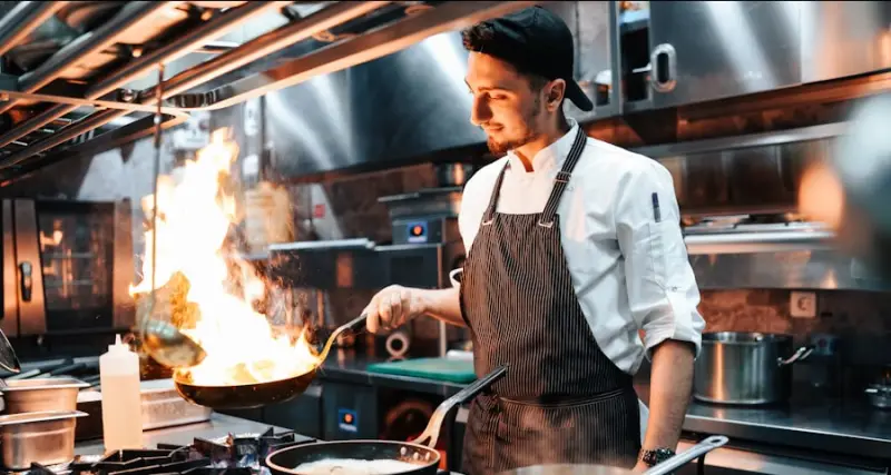 Chef cooking over a flame in a restaurant kitchen