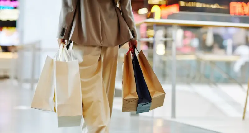 Shopper carrying bags through a retail store